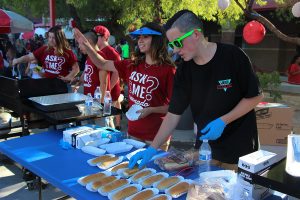 In the summer heat, Sofia Rosario, 9, and Tony Wright, 10, greet students and prep hot dogs for the Freshman BBQ Thursday, Aug. 10. By Haile Foster