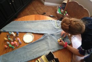 After buying a pair of mom jeans at Goodwill, Alli Harper, 10, decorates her jeans to fit her unique style with fabric paint. Photo by Maddie Baker