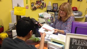 Choosing to buy the school agenda, John Jarvis, freshman, makes his purchase from Mrs. Ballard, the school banker.