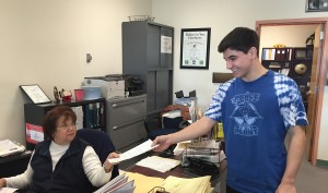 Turning in the DMV 130 form on Jan. 9 to Ms. Rojas in the attendance office, Nick Trejo, senior, takes the required steps to keep his license. (Photo by Lauren Smith)