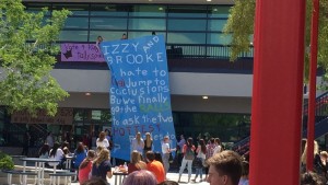 During second lunch in the quad on Wed. April 12, seniors, Rami Khalaf, and Michael Vanlaar unfold a banner asking juniors, Brooke Gibson, and Izzy Schmidt to prom. Photo by Ryann Heilen